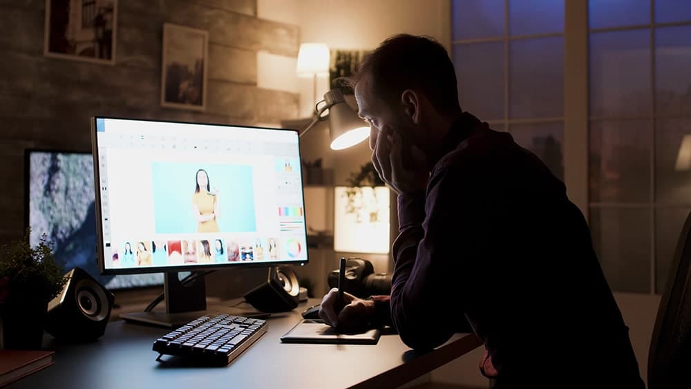 Hombre delante de un ordenador mirando la calidad de color de unas imágenes.